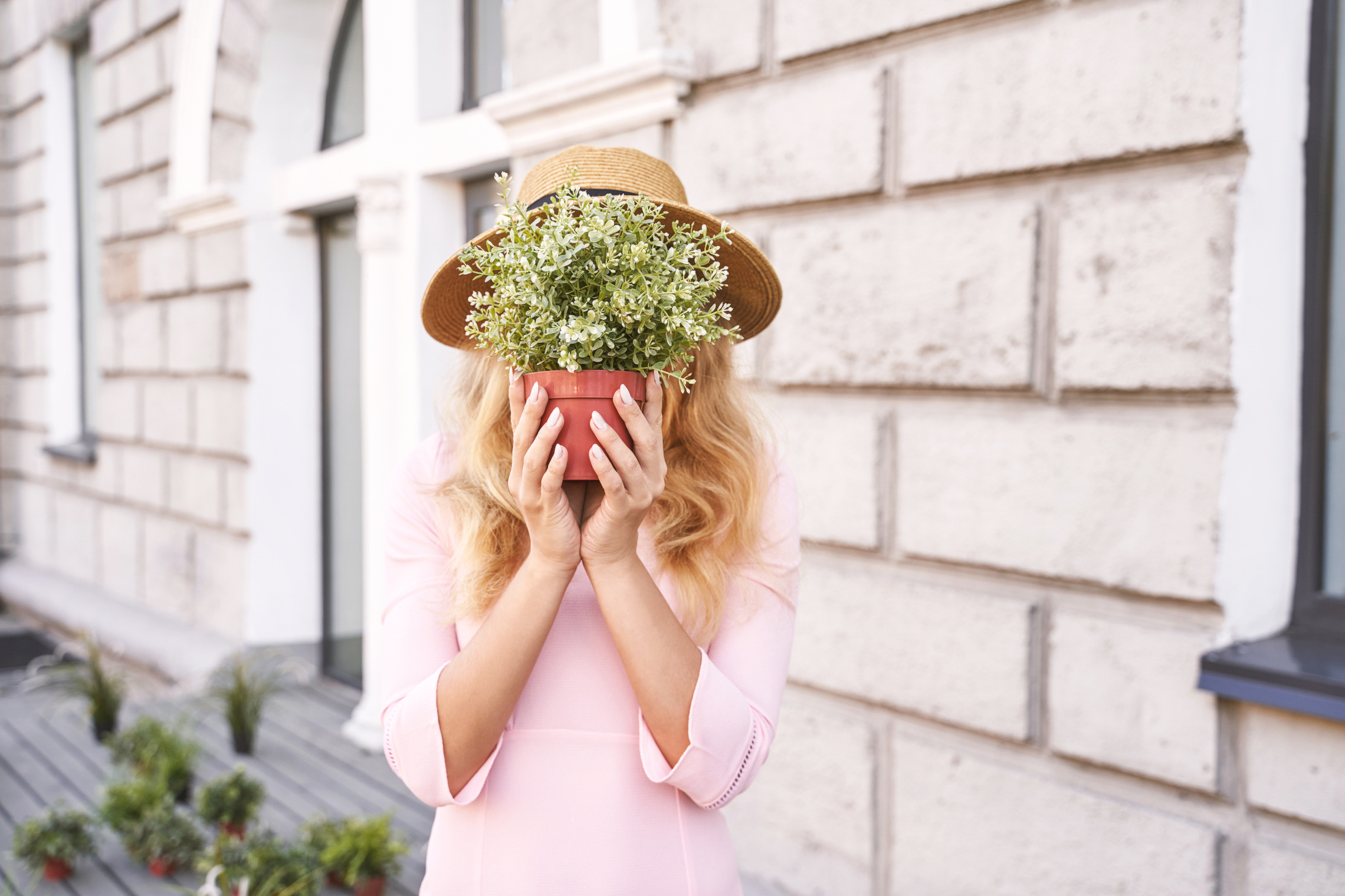 Young Woman Hiding face with Potted Plant