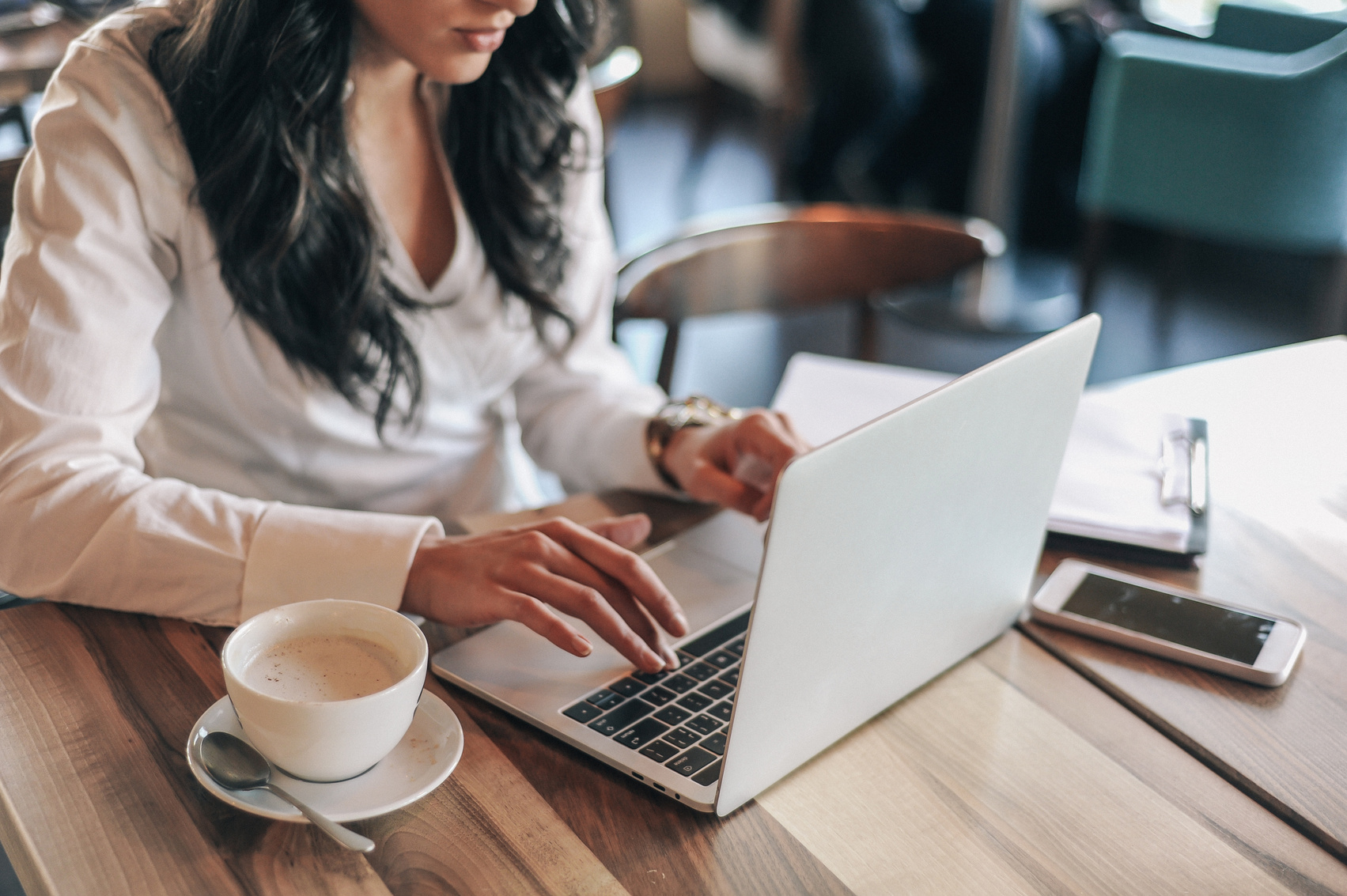 Woman Typing on a Laptop at a Cafe