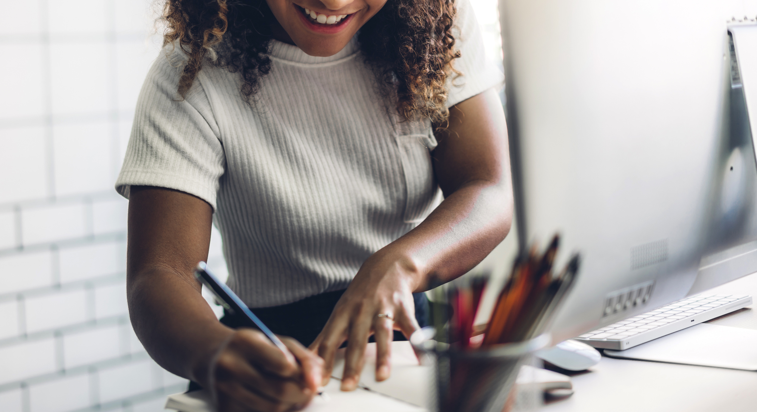 Woman Writing on a Notebook at a Work Desk 